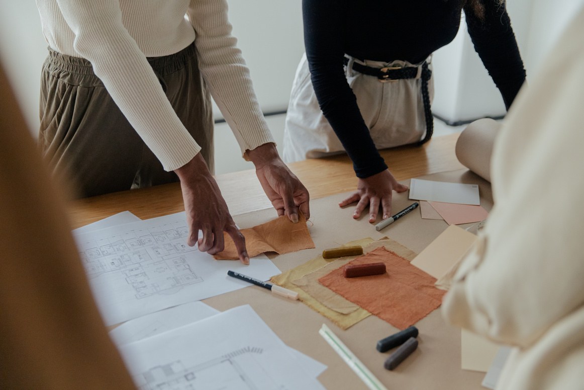 Team collaborating over design materials and fabric swatches on a table