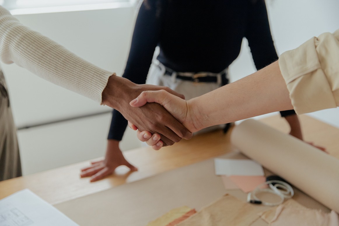 Handshake between two business partners over a table with design materials